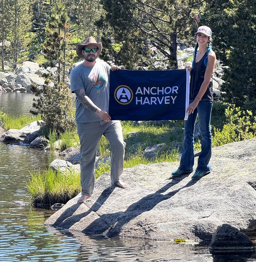 two individuals holding anchor harvey banner face to camers